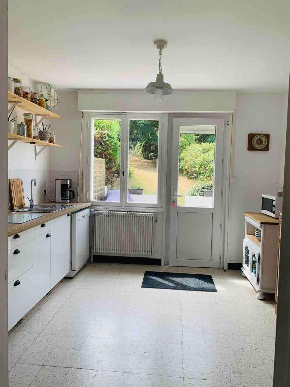 a kitchen with white cabinets and a large door at Entre mer et falaises in Équihen-Plage
