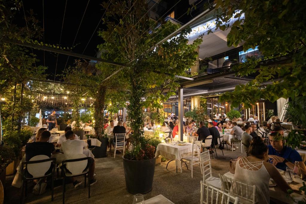 ludzie siedzący przy stolikach w restauracji w nocy w obiekcie Mustafa Suites we Wlorze