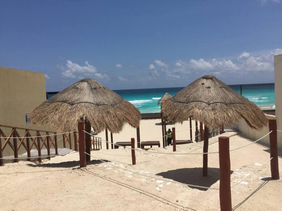 坎昆的住宿－Perla y Tropical By Andiani，海滩上的两把草伞和大海