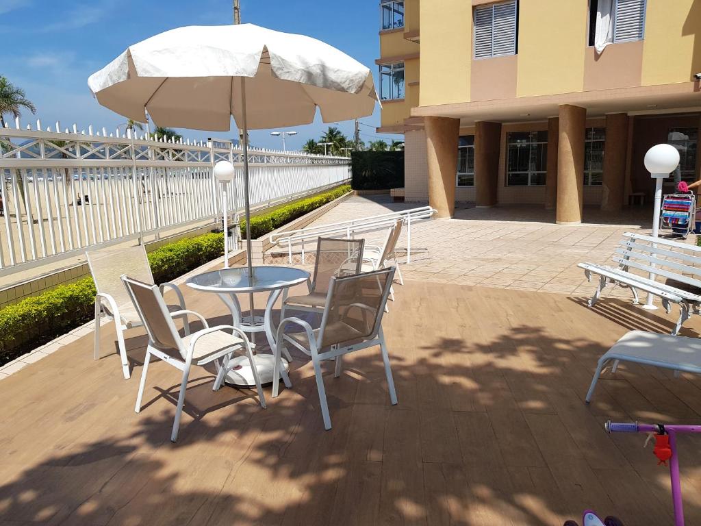 eine Terrasse mit Tisch und Stühlen und einem Sonnenschirm in der Unterkunft Verdadeiro Pé na Areia in Santos