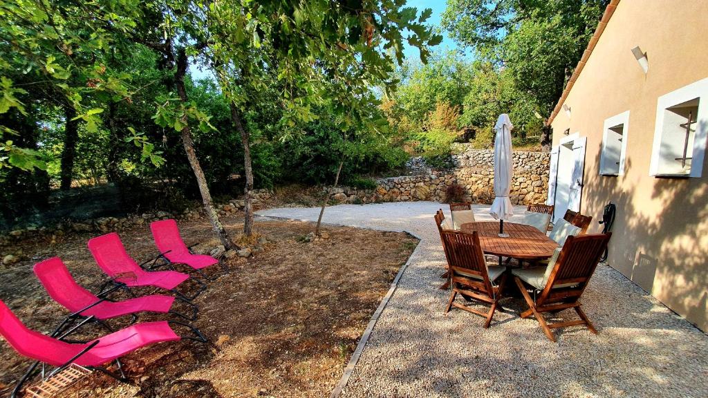 une terrasse avec des chaises roses, une table et des chaises dans l'établissement La Bergeronnette, à Saint-Paul-en-Forêt