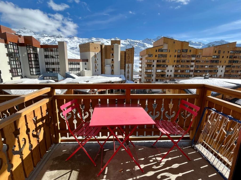 a red table and chairs on a balcony with snow covered mountains at Val Thorens Studio 4 pers Résidence La Roche Blanche in Val Thorens