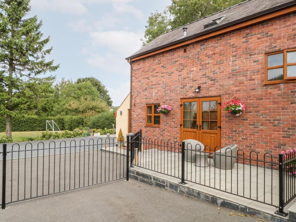 uma casa de tijolos com uma cerca e uma porta de madeira em Ash Farm Cottage em Holywell