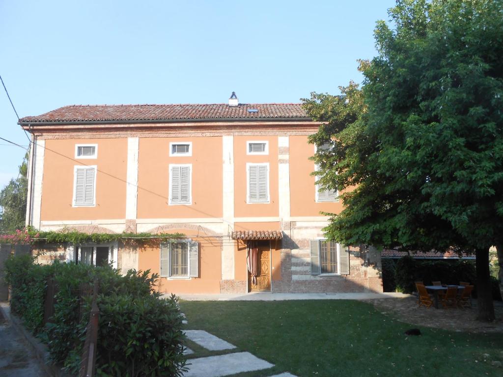 een groot oranje huis met een boom ervoor bij Agriturismo Azienda Agricola Mombisaggio in Tortona
