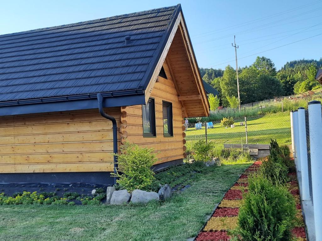 a wooden house with a black roof at Domek na szlaku RIKARDO in Ponice