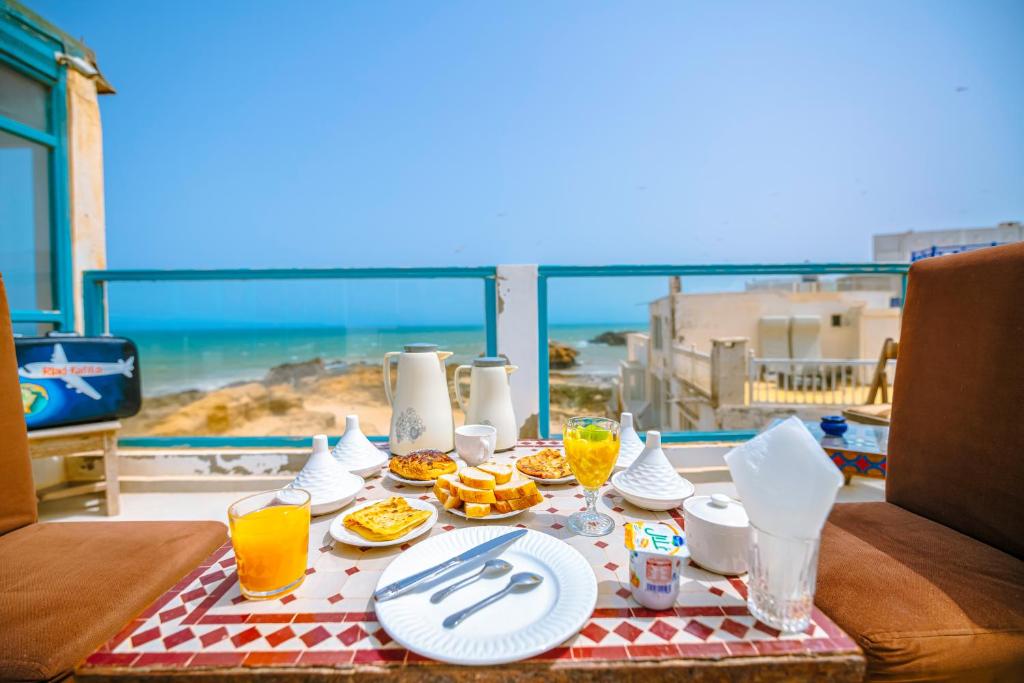 stół z jedzeniem i widokiem na ocean w obiekcie Riad Kafila w mieście As-Suwajra