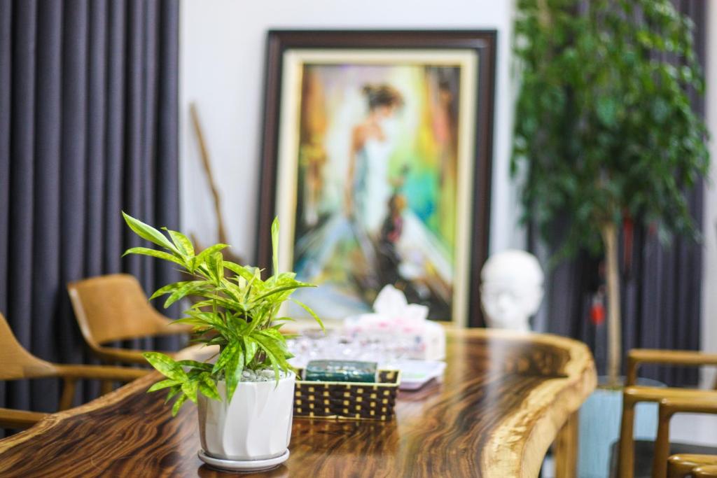 a wooden table with plants on it with a painting at Green Line Long Bien - Serviced Apartment - Ngoc Thuy - Hanoi in Hanoi
