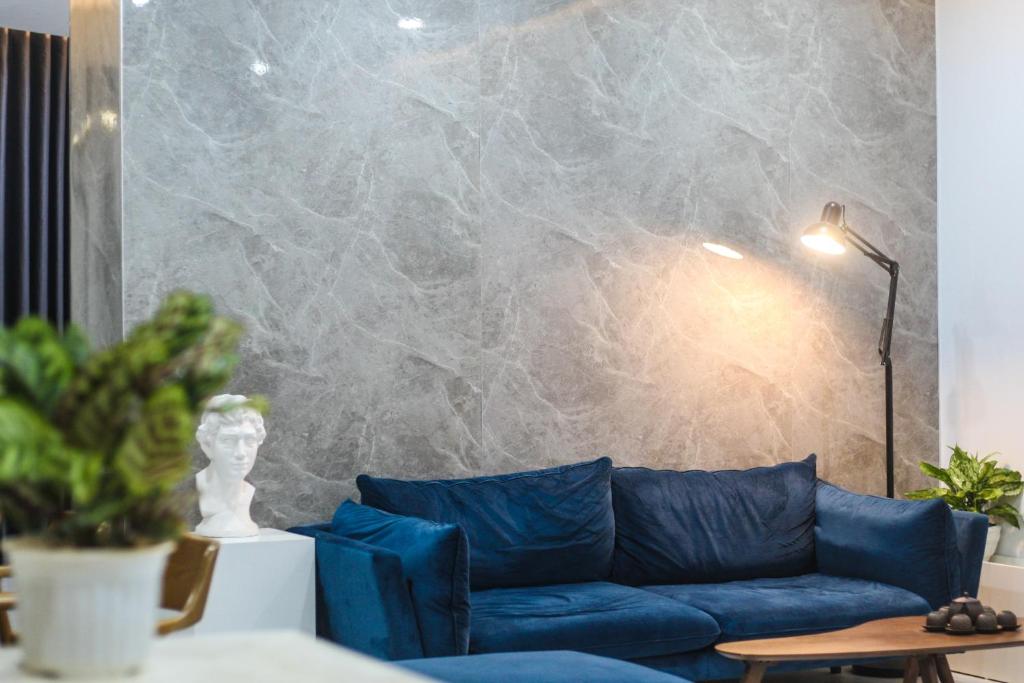 a blue couch in a living room with a marble wall at Green Line Long Bien - Serviced Apartment - Ngoc Thuy - Hanoi in Hanoi