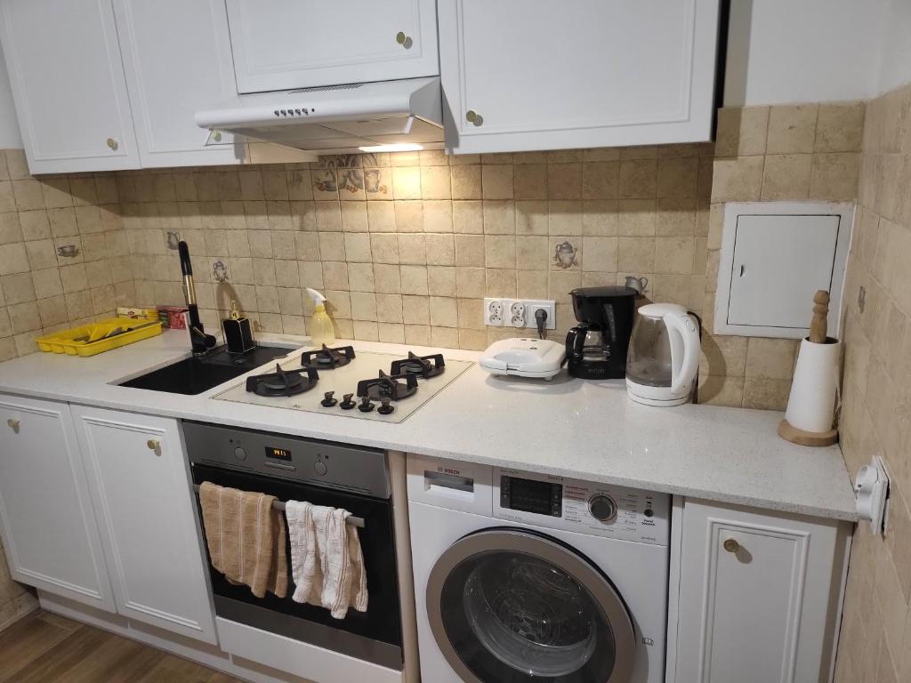 a kitchen with a stove and a washing machine at Studio Żelazna - Apartment near Old Town in Warsaw