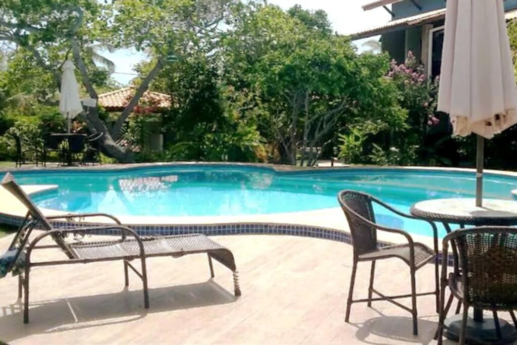 uma mesa e cadeiras ao lado de uma piscina em Imbassai - Casa Alto Padrão completa - Condominio Fechado - A2B3 em Imbassaí