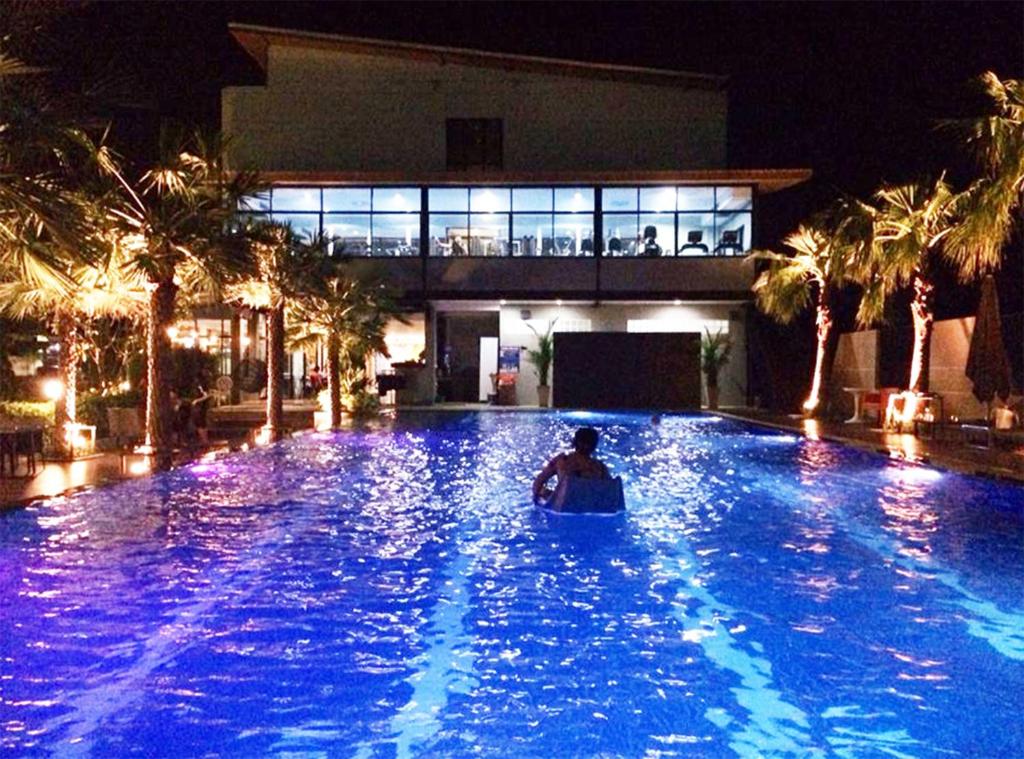 una persona en una piscina en un complejo por la noche en Ray Hotel Buriram, en Buriram