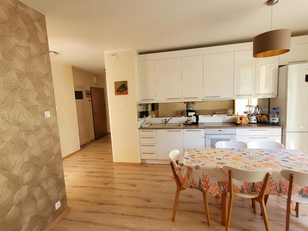 a kitchen with a table and chairs and white cabinets at Comfort Warszawa in Warsaw