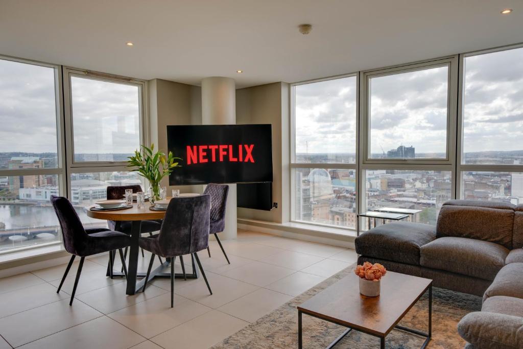 a living room with a tv and a table and chairs at TALLEST BUILDING IN THE CITY CENTRE SLEEPS 5 incredible city mountain and Lagan views in Belfast