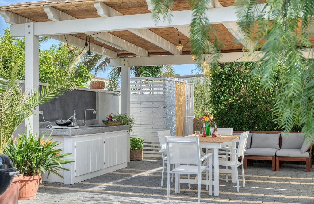 un patio avec une cuisine, une table et des chaises dans l'établissement La Casa degli Ulivi appartamento in villa con patio, à Quartu SantʼElena