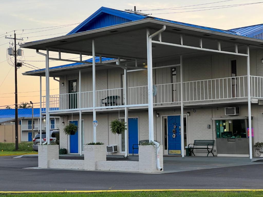 - un bâtiment avec une terrasse couverte et des portes bleues dans l'établissement Towne inn, à Sylacauga
