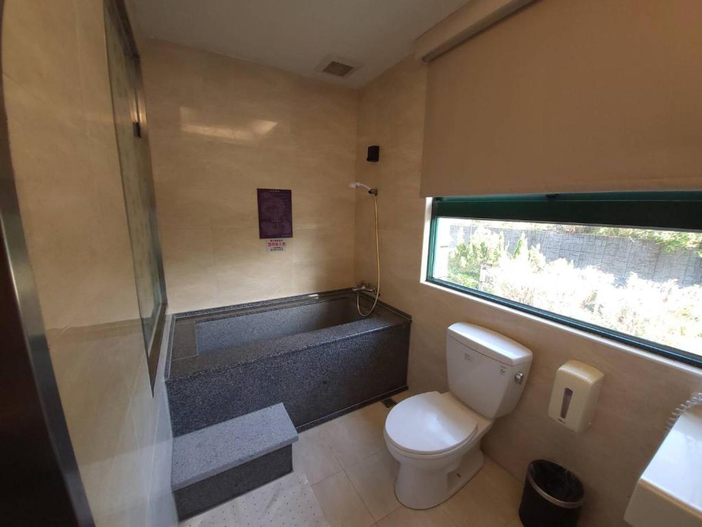 a bathroom with a toilet and a bath tub at Jin Yong Quan Spa Hotspring Resort in Wanli District