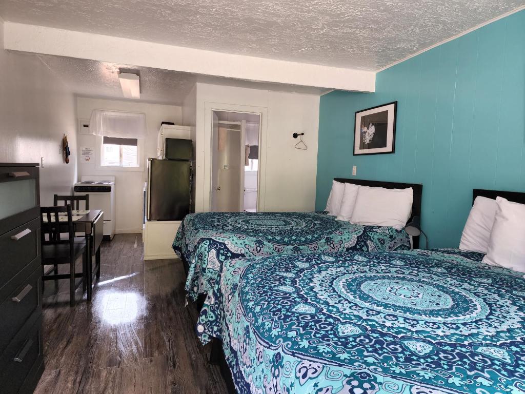 a room with two beds and a table and a kitchen at Plainview Motel in Coos Bay