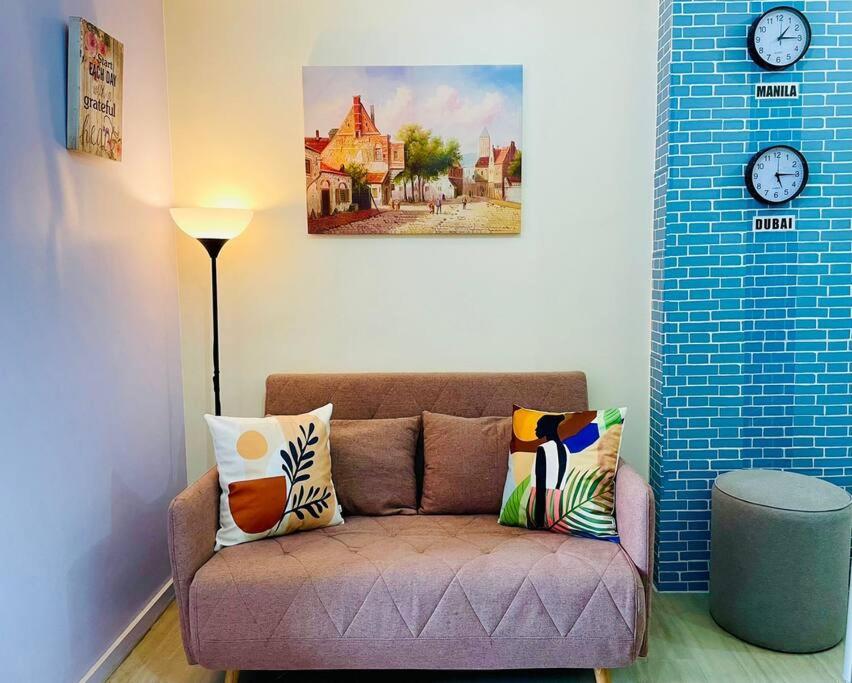 ein Wohnzimmer mit einem Sofa und einer Uhr an der Wand in der Unterkunft Amaia Steps Bicutan with Netflix and DisneyPlus - 1BR in Manila