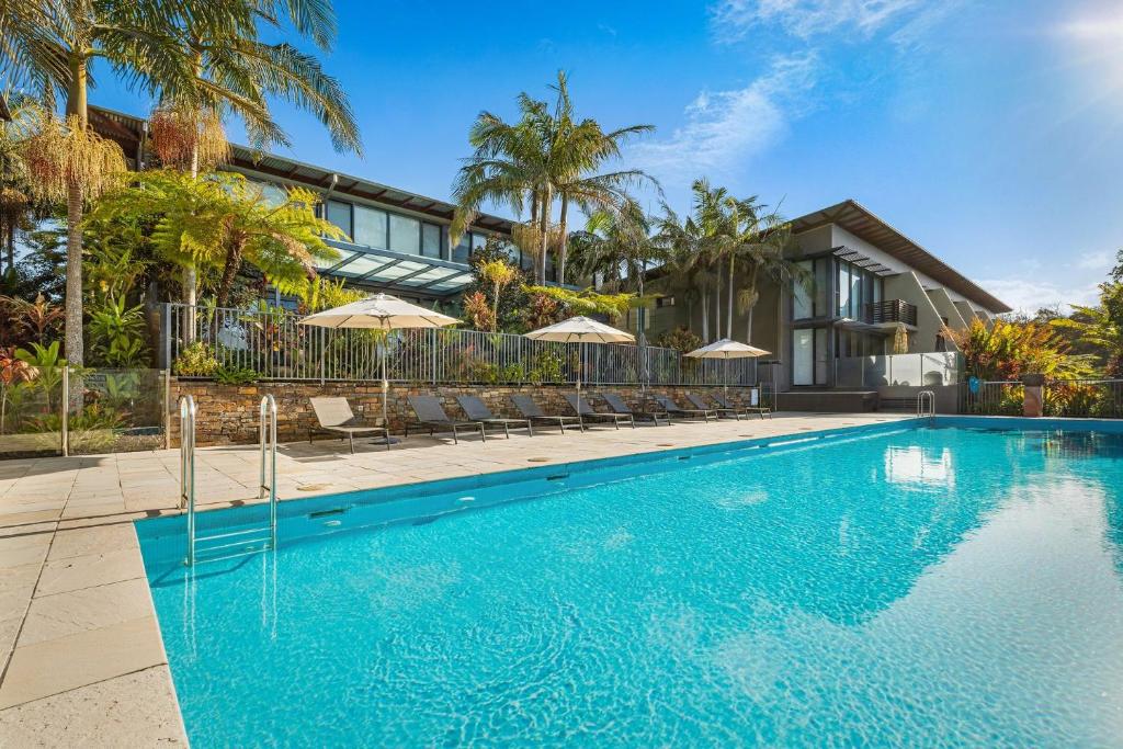 a swimming pool in front of a house with umbrellas at Your Luxury Escape - Kiah 11 Beach House Ocean views in Byron Bay