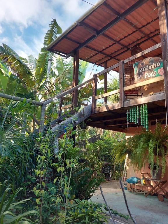 a wooden building with a deck in a garden at Hospedaria Recanto da Paz in Itaporanga dʼAjuda