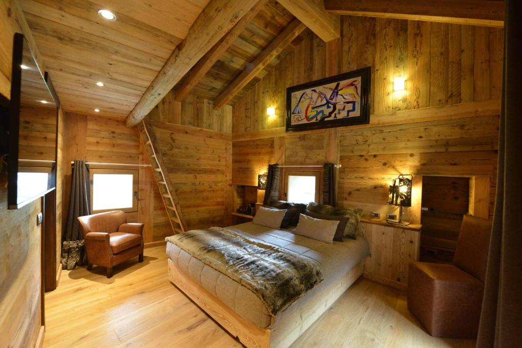 1 dormitorio en una cabaña de madera con 1 cama y 1 silla en La Maison de Dolphe Chalet de Charme & Art gallery, en Brusson
