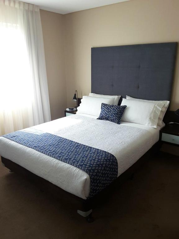 APARTMENT@96 في أديلايد: غرفة نوم بسرير كبير ومخدات زرقاء وبيضاء