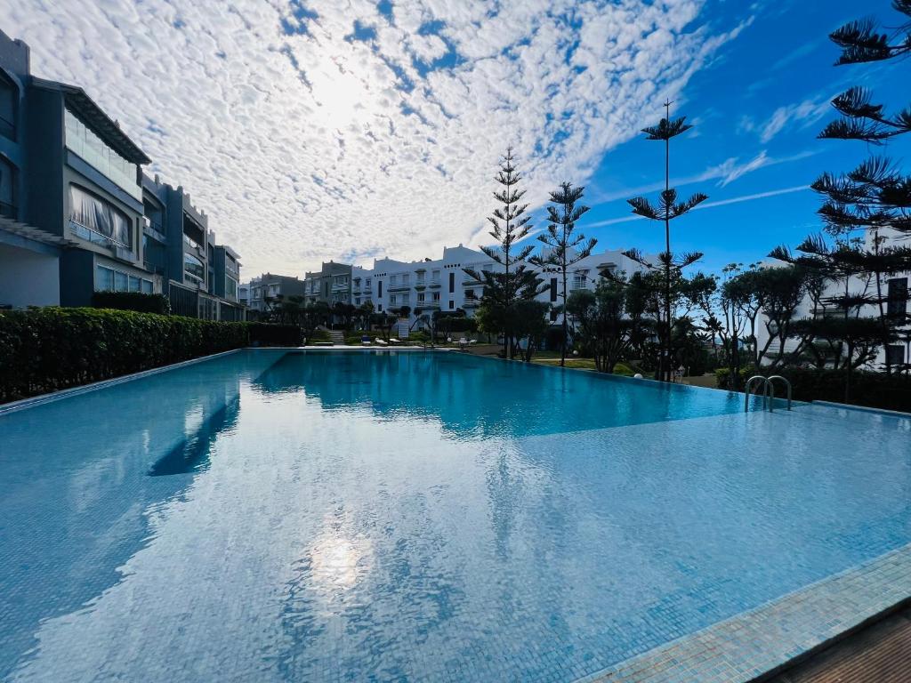 Melrose Beαch Aρραrt Pοοl Vieω في الدار البيضاء: حمام سباحة أزرق كبير مع سماء غائمة