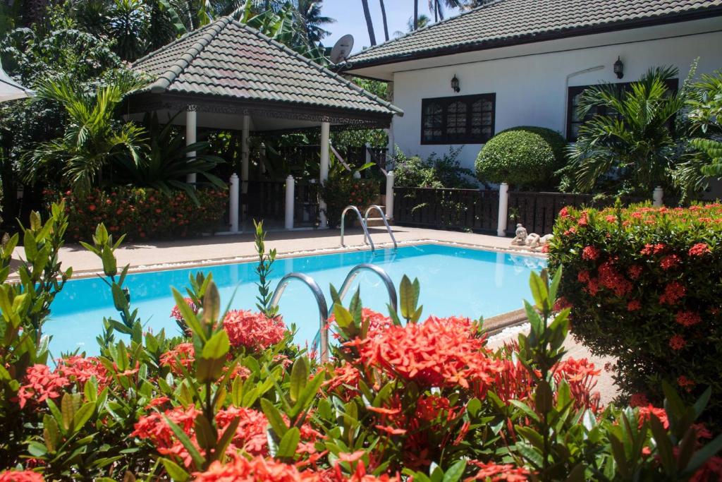 a swimming pool with flowers in front of a house at Baan Sawainam in Ko Tao