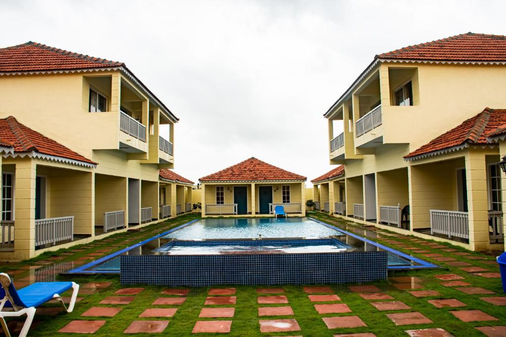 The Village Resort Mundra في Mundra: مسبح في ساحة مبنى