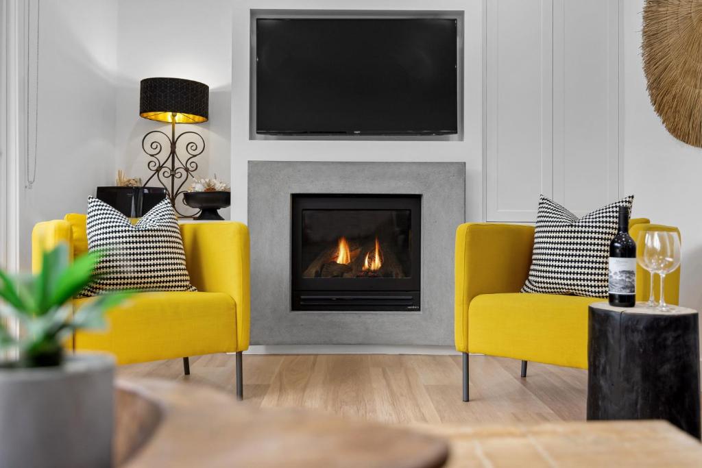 sala de estar con 2 sillas amarillas y chimenea en Capella Villa No. 2 - luxury with outdoor kitchen, en Blairgowrie