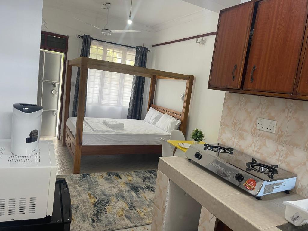 Una pequeña habitación con una cama y una cocina. en Urban studios, en Kilifi