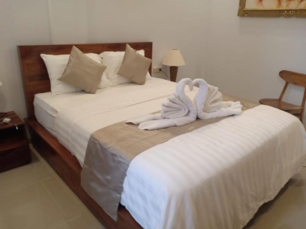 two beds with white sheets and towels on them at D'TRANSIT in Nusa Penida