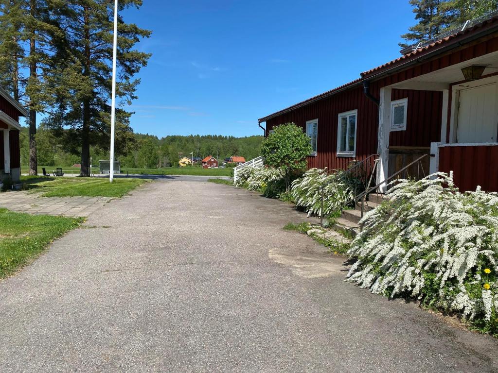 een weg naast een rood gebouw met bloemen bij Skogshemmet in Ludvika