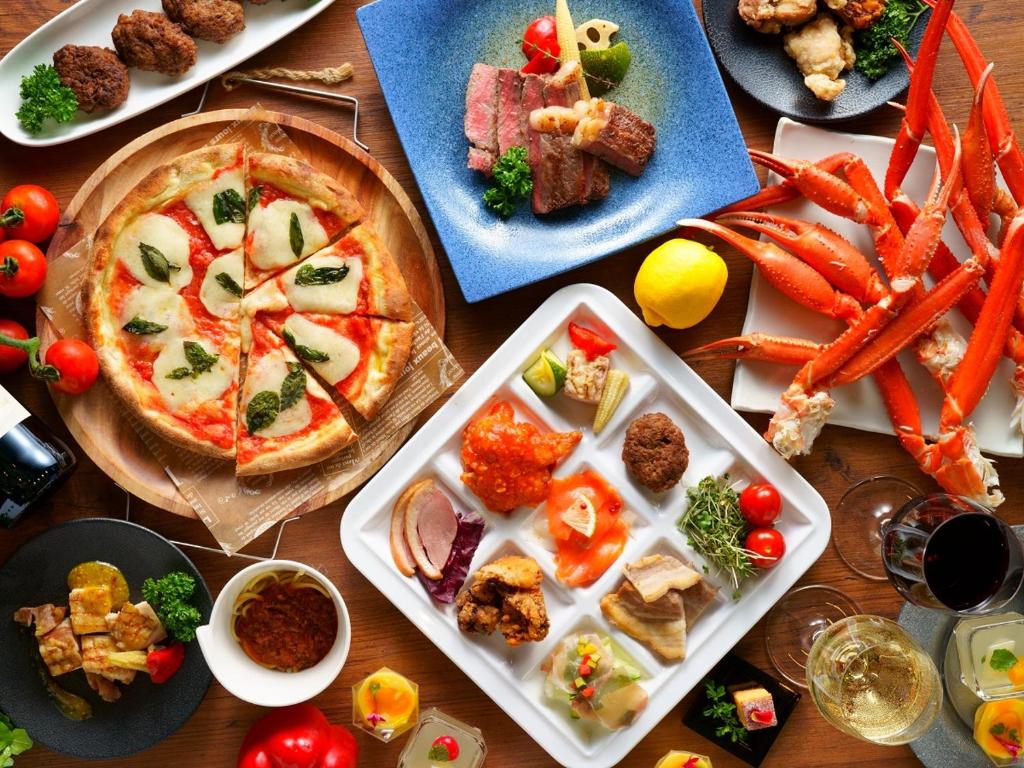 Aso Resort Grandvrio Hotel في آسو: طاولة مليئة بأطباق الطعام والبيتزا