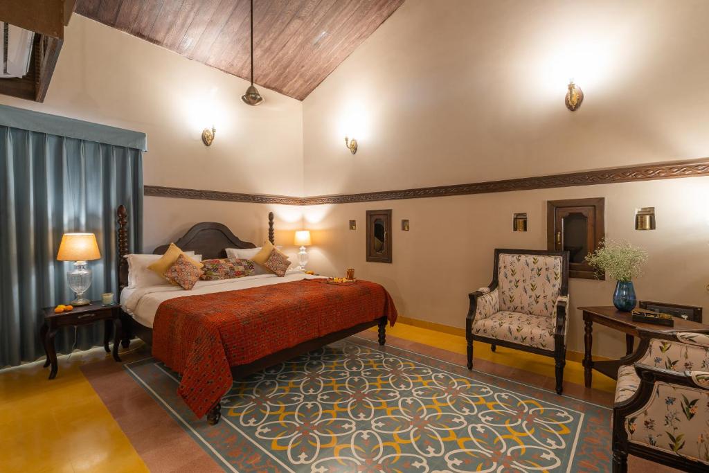 ein Schlafzimmer mit einem Bett und einem Stuhl in der Unterkunft Tree of Life Darbargadh Dared in Bhavnagar