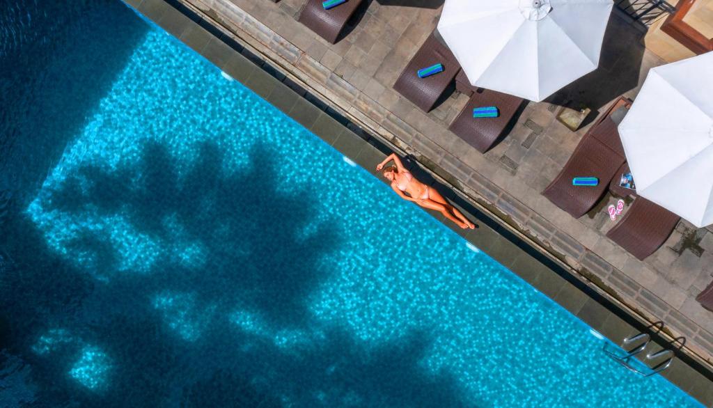an overhead view of a swimming pool with a persons shadow in the water at Solia Legian Bali in Legian
