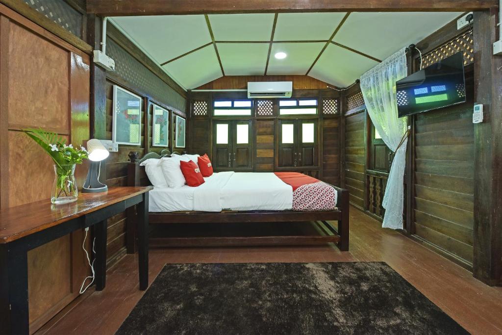 een slaapkamer met een bed, een bureau en een televisie bij Collection O 90622 Sehijau Cenang in Pantai Cenang