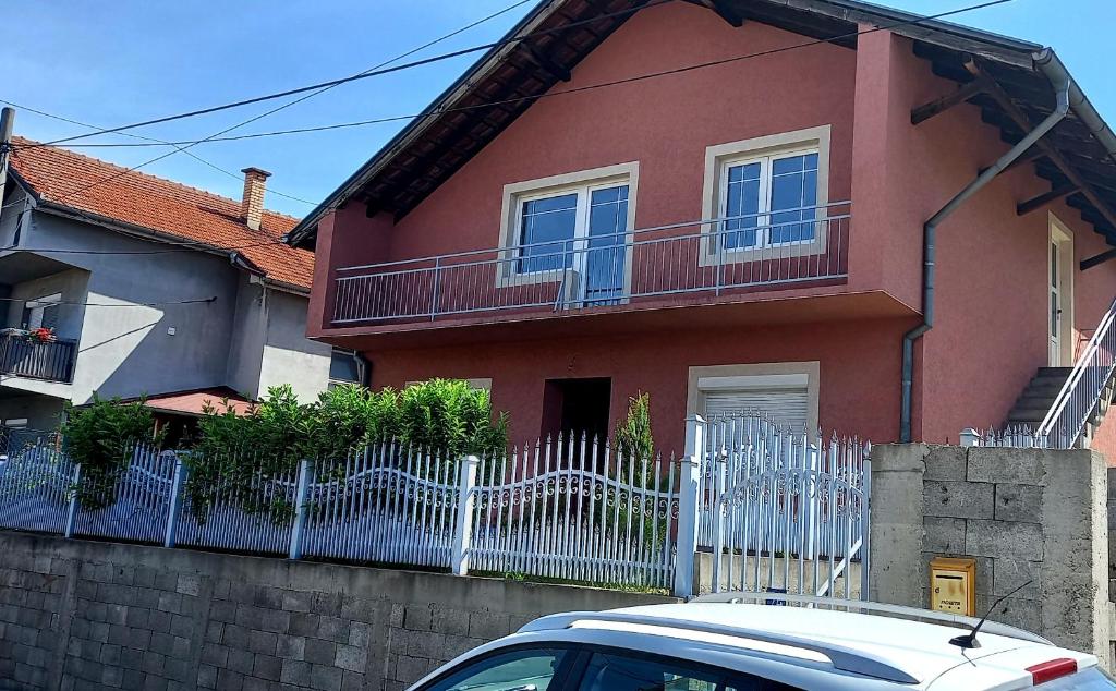 a red house with a white fence and a car at Serbian home Smederevo in Smederevo