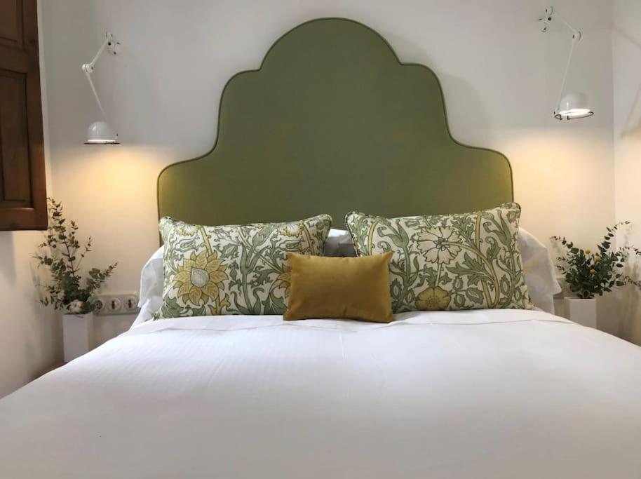 1 cama blanca grande con cabecero verde y almohadas en Lloēco - Art & Design Guest House en León