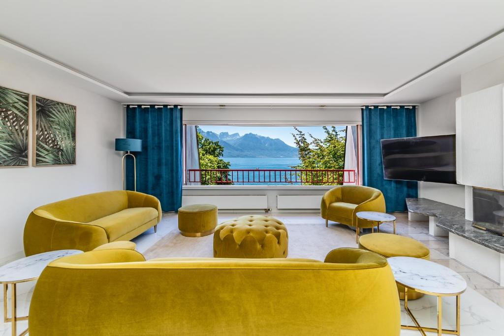a living room with yellow furniture and a large window at Bon-Port Luxury apartment - Lakefront in Territet