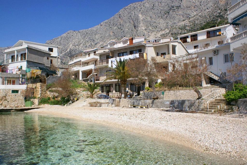 a group of buildings on a beach next to the water at Apartments by the sea Drasnice, Makarska - 15927 in Drasnice