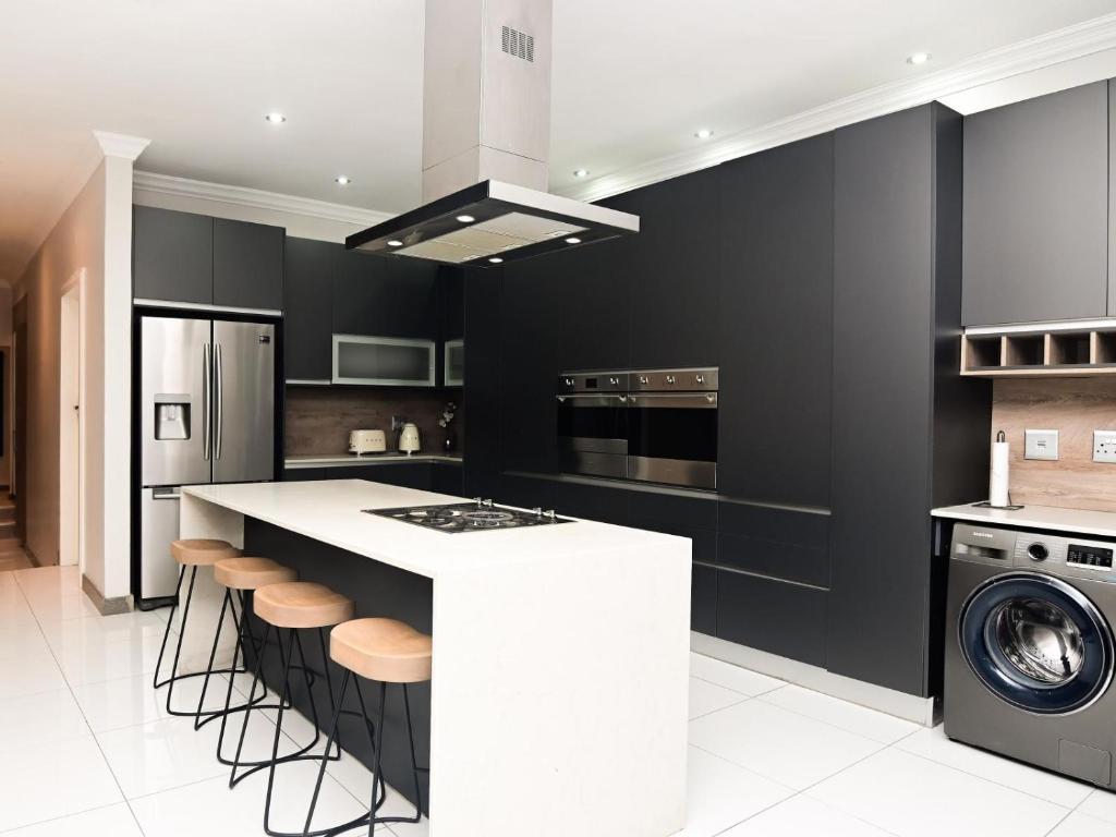 een keuken met zwarte muren en een keukeneiland met krukken bij Sou House in Louis Trichardt