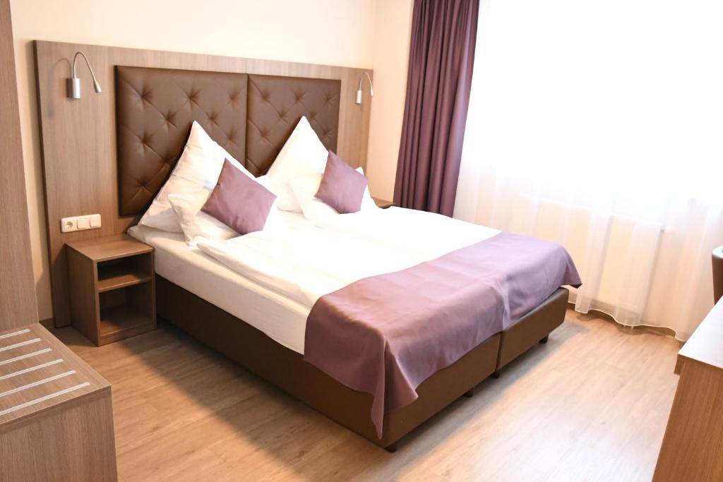 1 dormitorio con 1 cama grande con almohadas en Ata Hotel - Self Check-in en Hamburgo