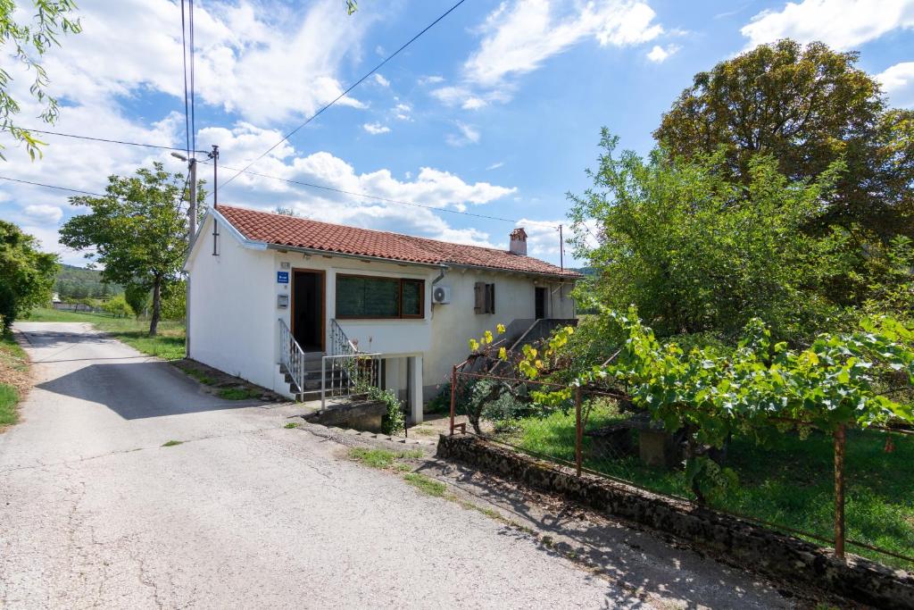een wit huis met een hek naast een weg bij Apartments with a parking space Buzet, Central Istria - Sredisnja Istra - 17333 in Buzet