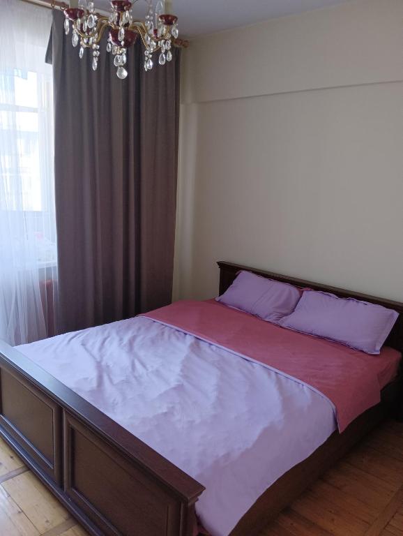 a large bed in a bedroom with a chandelier at Квартира на Абая in Almaty