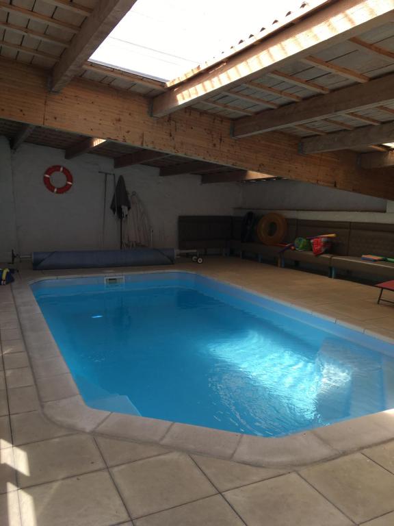 uma grande piscina azul sob um telhado em Gites Le Cheval Noir em Rouillac