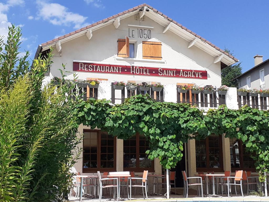 a building with tables and chairs in front of it at Logis Hôtel Restaurant Le 1050 in Saint-Agrève