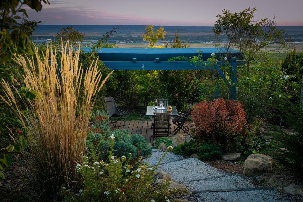 un jardin avec une table et une pergola bleue dans l'établissement Le Charme, à Cernay-lès-Reims