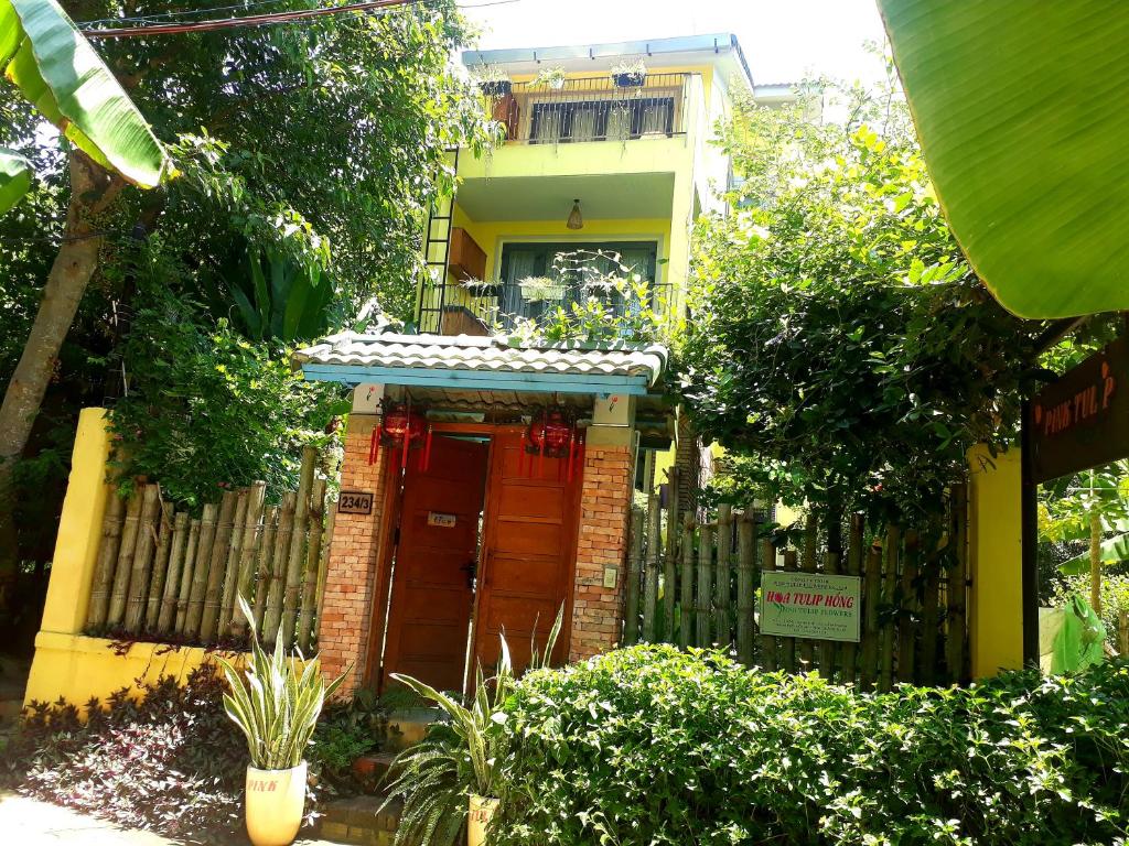 een huis met een rode deur en een hek bij Pink Tulip Hoi An in Hội An