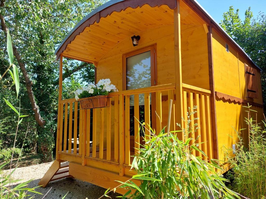 een houten hut met een veranda en een raam bij La Roulotte du Herdal in Profondeville